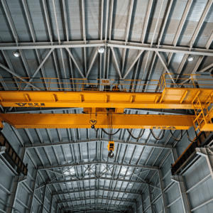 Double girder overhead crane lifting heavy industrial load in factory workshop