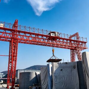 Double girder truss gantry crane handling heavy concrete components in an outdoor concrete fabrication yard